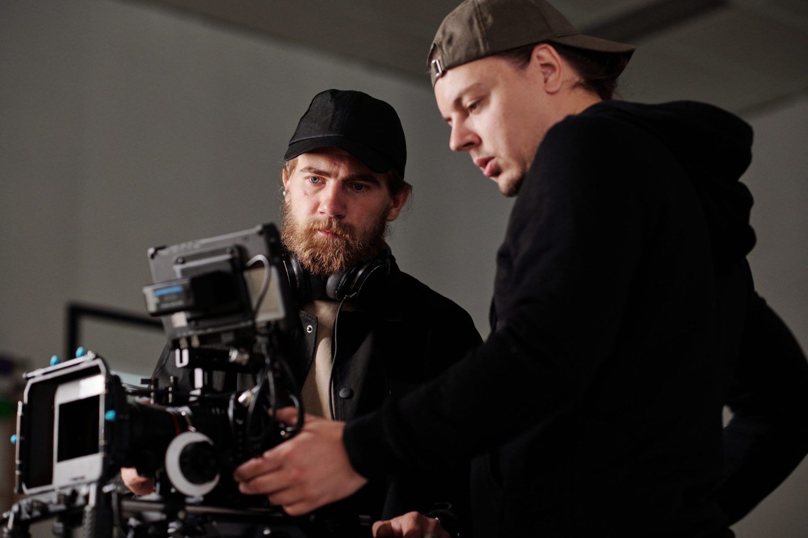 Two serious men in black sweatshirta discussing settings of steadicam